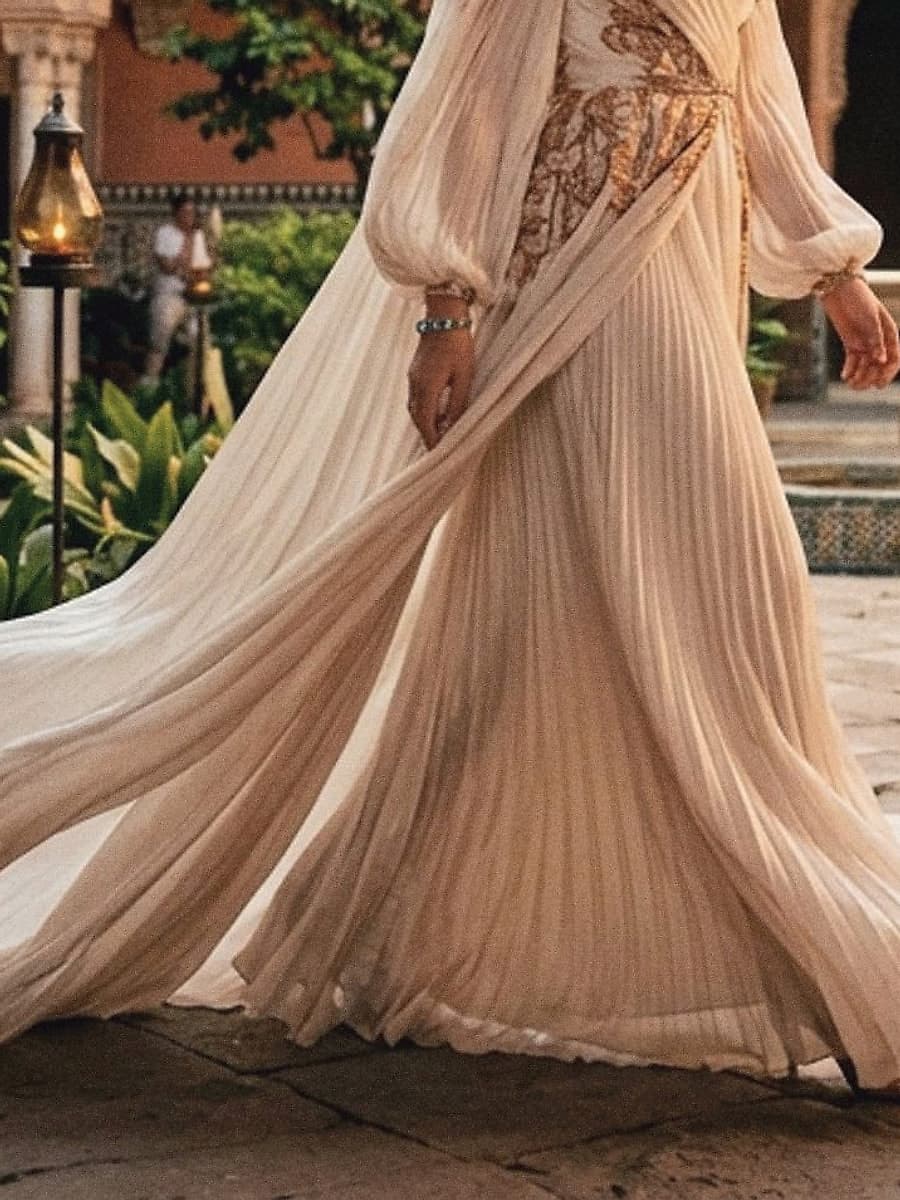 The pleated hem in motion across courtyard stone